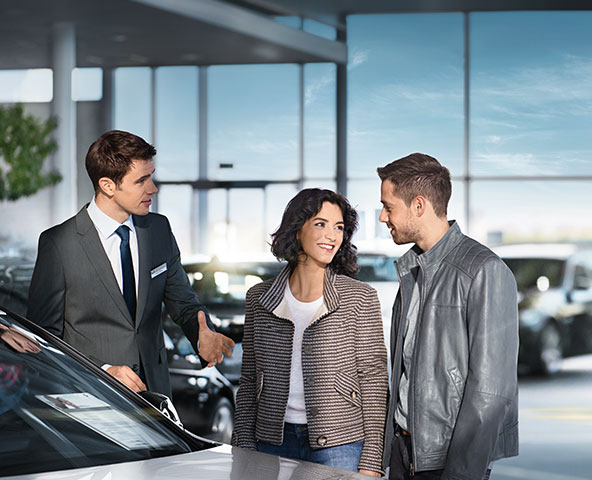 Happy couple being shown to their leased BMW car by a Customer Service Advisor.